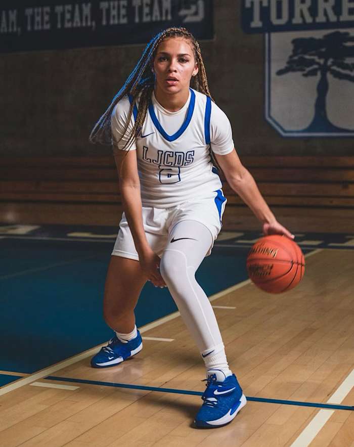 Jada Williams dribbles a basketball in her high school gym